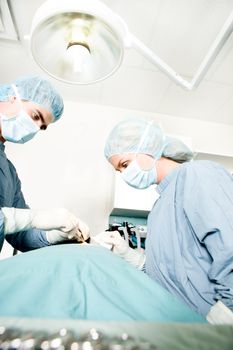 A surgeon working in a small operating room with an assistant