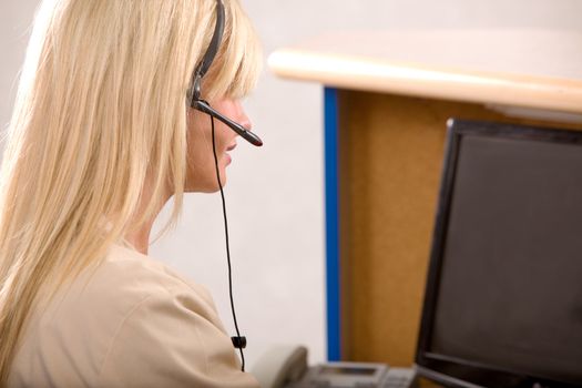 A receptionist working at a computer with a headset