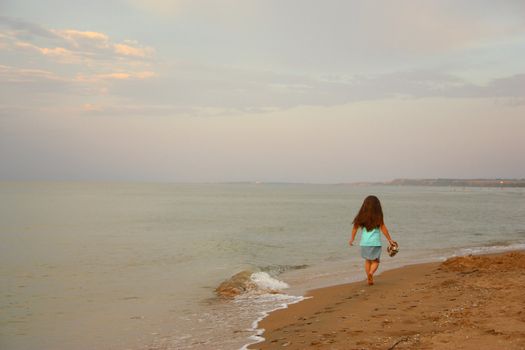 Little girl walks barefoot on seacoast