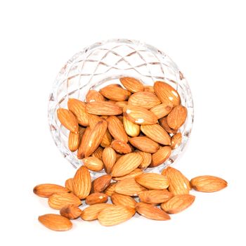 A glass bowl of almonds isolated on white