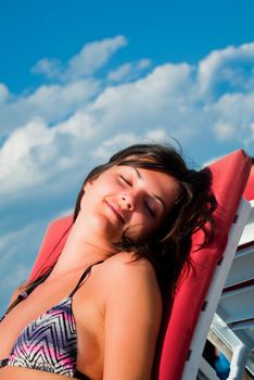 Beautiful girl enjoying the sun at the seaside on a beach chair