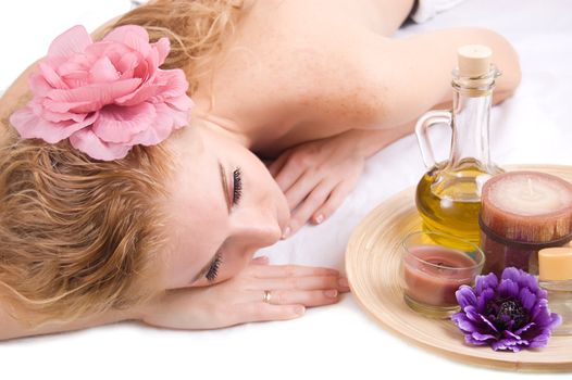 Redheaded woman lying with spa products over white