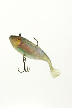 A multi colored artificial lure floating against white