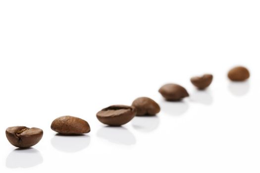 diagonal row of coffee beans on white background