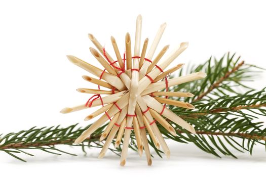 straw star in front of a branch on white background