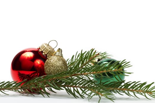 three christmas balls between a branch on white background
