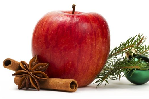 red apple, star anise, cinnamon sticks, a green christmas ball and a branch on white background