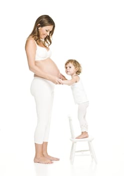 Pregnant woman with her daughter standing on a chair
