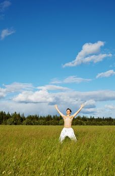 The young man is happy - has emotionally thrown up hands in a green field