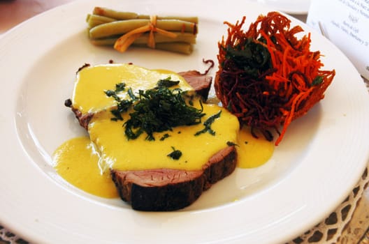 Delicious meat with yellow creamy sauce and vegetable