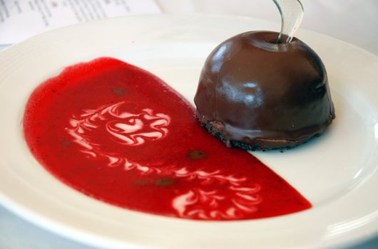 Chocolate dessert with red strawberry sauce on white plate