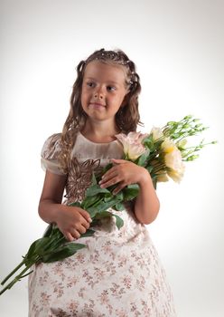 Cute little girl with pigtail hairstyle holding flowers, studio shot  