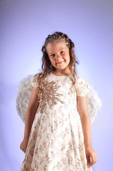 Cute little girl with pigtail hairstyle and angel wings, studio shot on purple background 