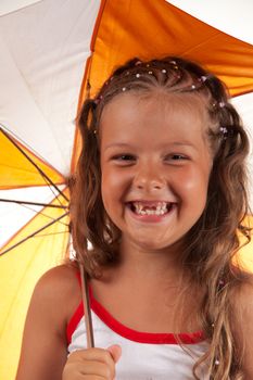 Little girl holding umbrella and showing two missing teeth, studio shot 