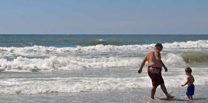 Father and Son Splash in the ocean