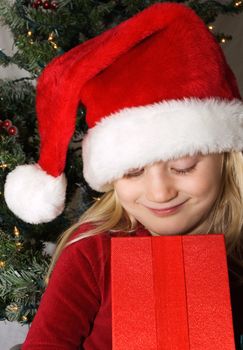 Young girl wearing santa hat looking into an open present