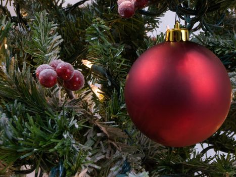 Christmas ornament on a tree with berries and lights