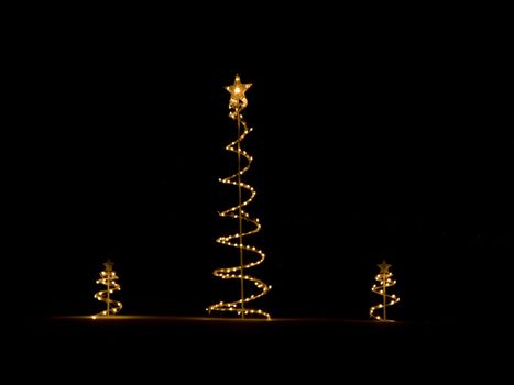 Three christmas tree decorations outside in the snow