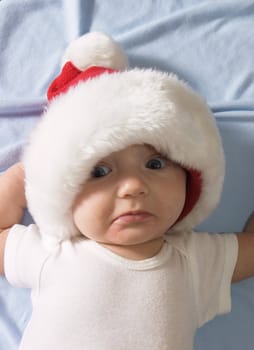 Baby wearing a santa hat with a frown on his face