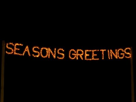 Seasons greetings lit up in lights at night time