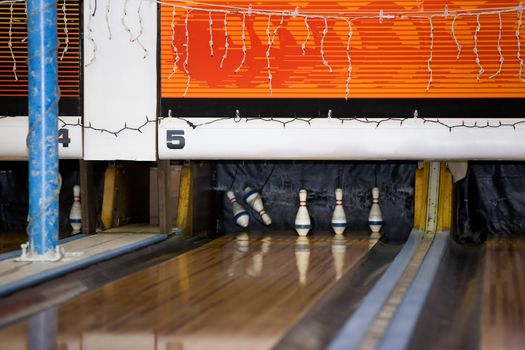 A retro bowling alley detail with 2 pins being knocked down.