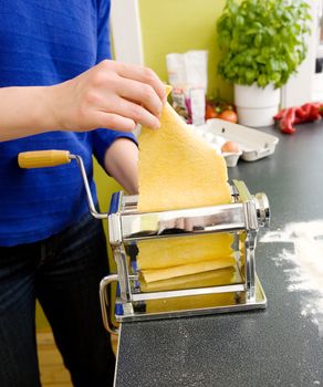 A young female makes pasta at home in the kicthen;