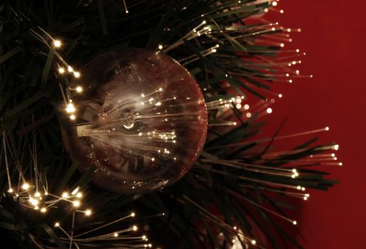Details of a fibre-optic decorated Christmas Tree against a red wall