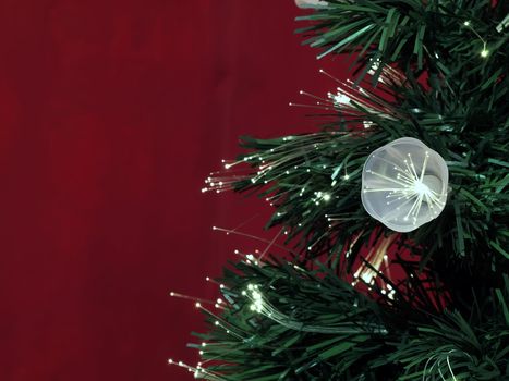 Details of a fibre-optic decorated Christmas Tree against a red wall