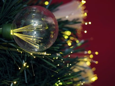 Details of a fibre-optic decorated Christmas Tree against a red wall