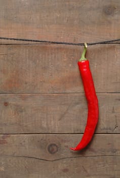 Red chili pepper hanging on wooden background with rope