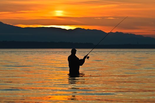 Silhouette of a fisherman with a fishing pole at sunset.