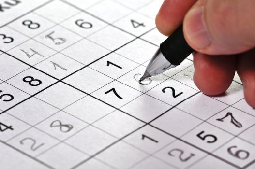 Close-up a pencil in hand and logic puzzle Sudoku.