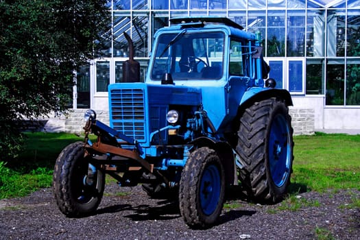 Painted in blue tractor standing before glass building