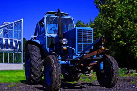 Painted in blue tractor standing before glass building