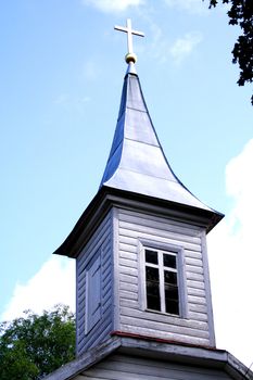 Wooden church tower with lighted cross on roof