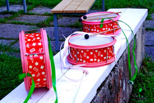 Pink and decorated drums laying on white bench