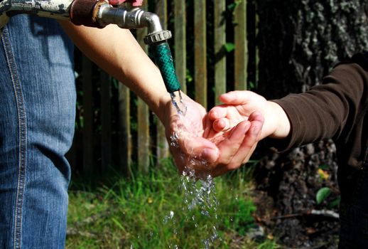 People washing ditrty hands under fresh water stream