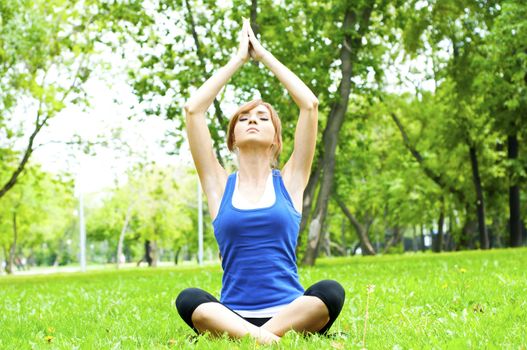 young woman is engaged in yoga, in summer on a green grass