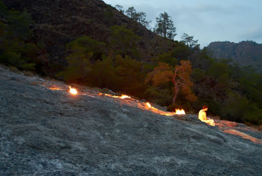 Alome man  near Chimaera natural gas flame on Yanartas mountain. Cirali Turkey