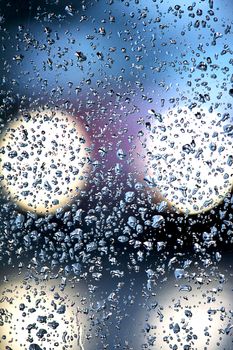 View of a glass with many droplets of water lit by a passing car.