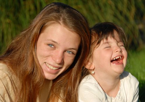 two smiling sisters: teenager and little girl

