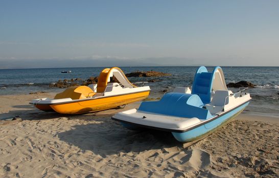 two blue and yellow pedallos on a beach of corse
