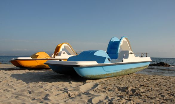 two blue and yellow pedallos on a beach of corse
