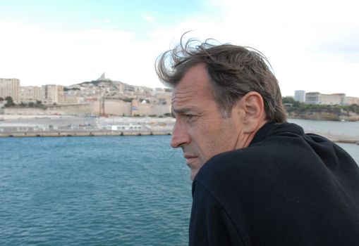 sad man watching the city of marseille in a boat

