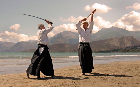two adultes are training in aikido on a beach in japon