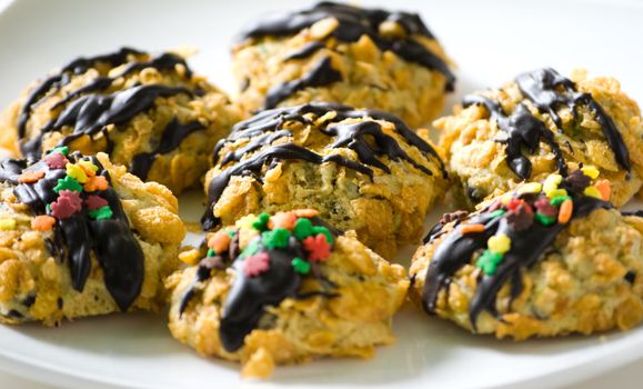 Cornflakes cereal cookies with chocolate sauce and colorful sprinkles