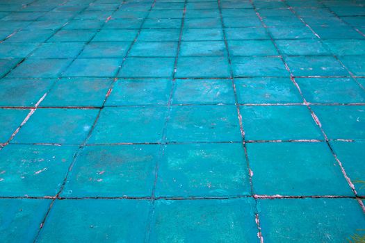 Concrete floor tiles painted aquamarine or turqoise in a diminishing perspective