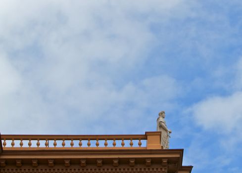 Courthouse statue of Themis Goddes of Justice standing on the edge of a roof