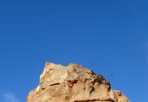 Some costal Cliffside rock against a blue sky.