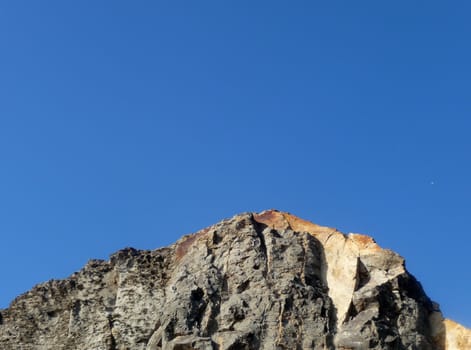 Some costal Cliffside rock against a blue sky.